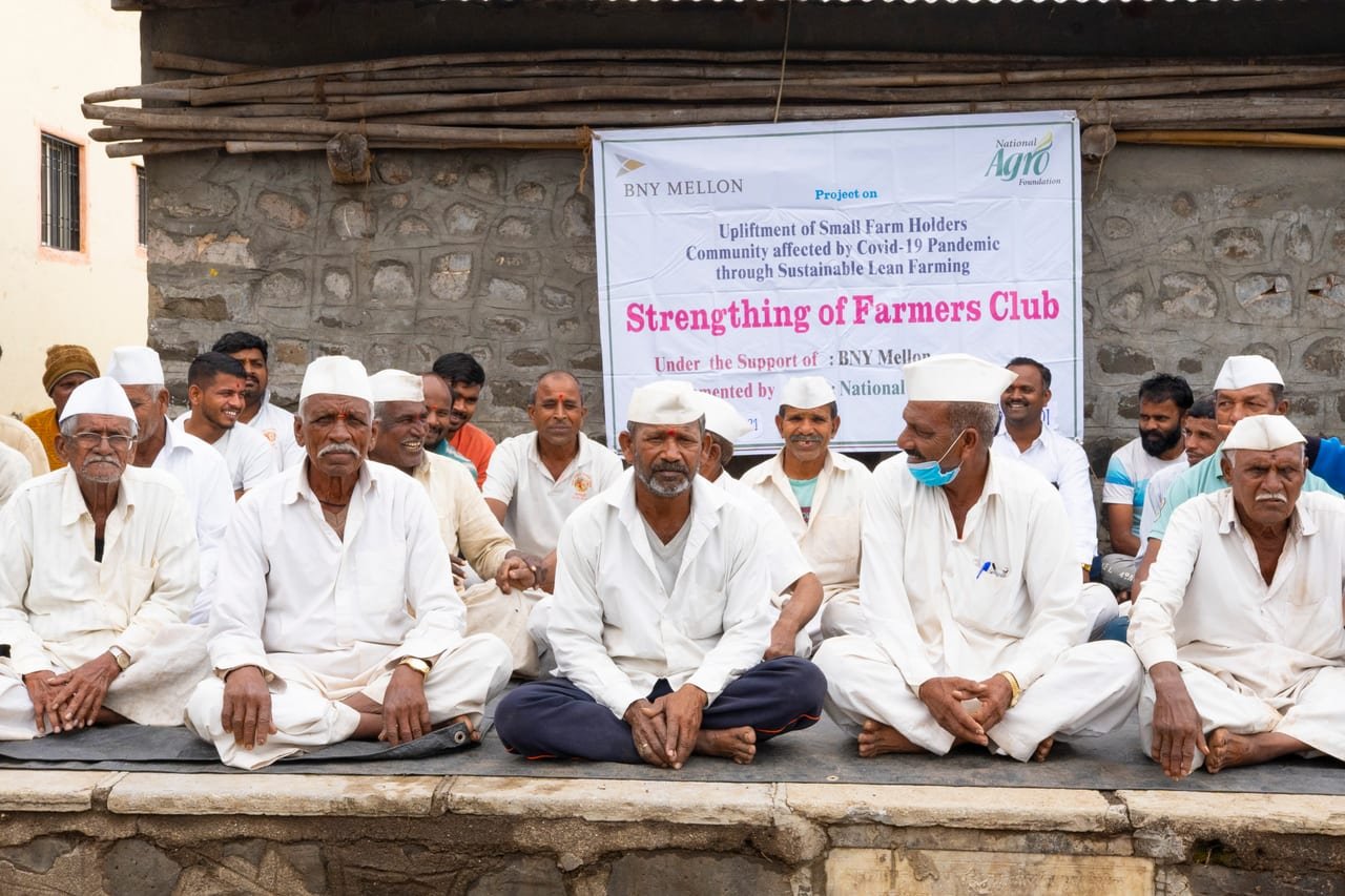 Farmers in white caps seated beneath a farmers' club meeting banner