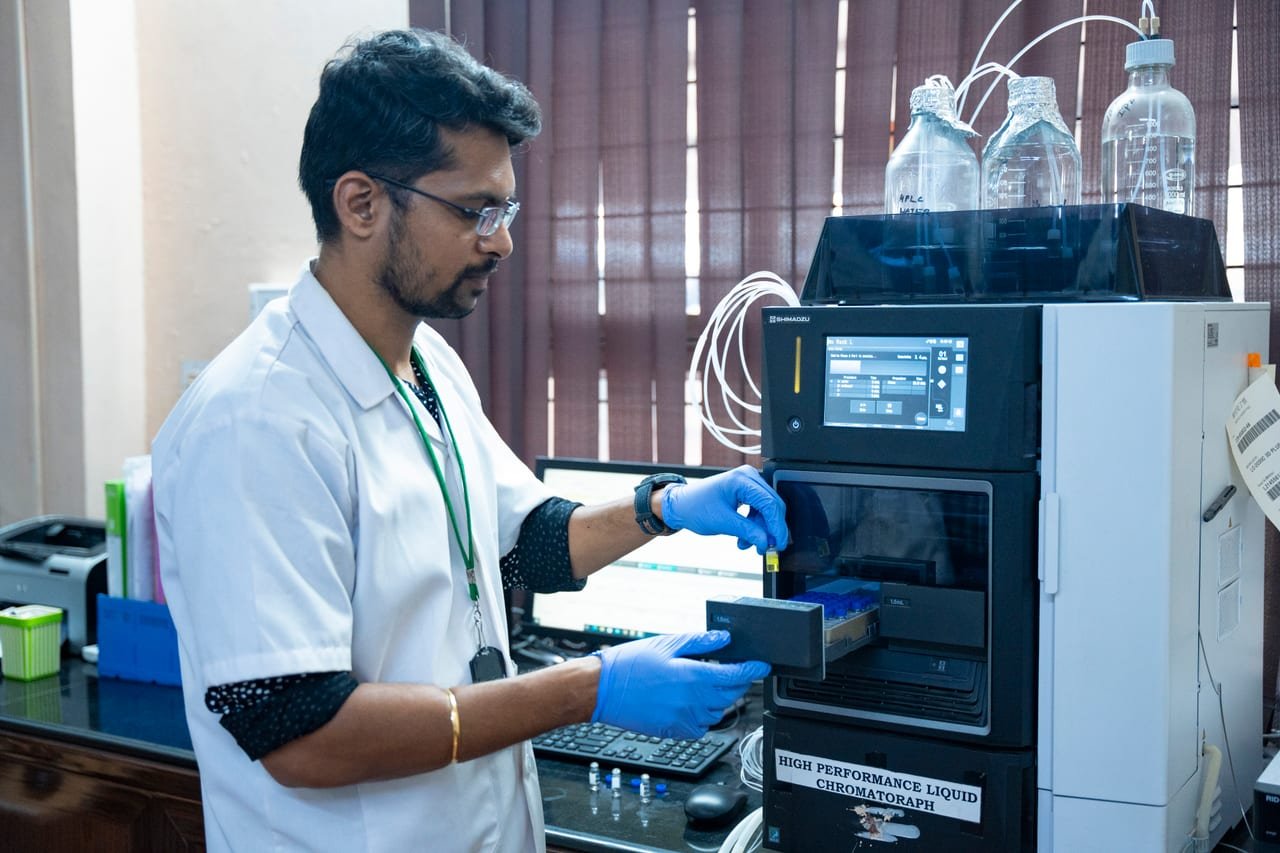 A laboratory analyst operating an analytical instrument with a sample tray