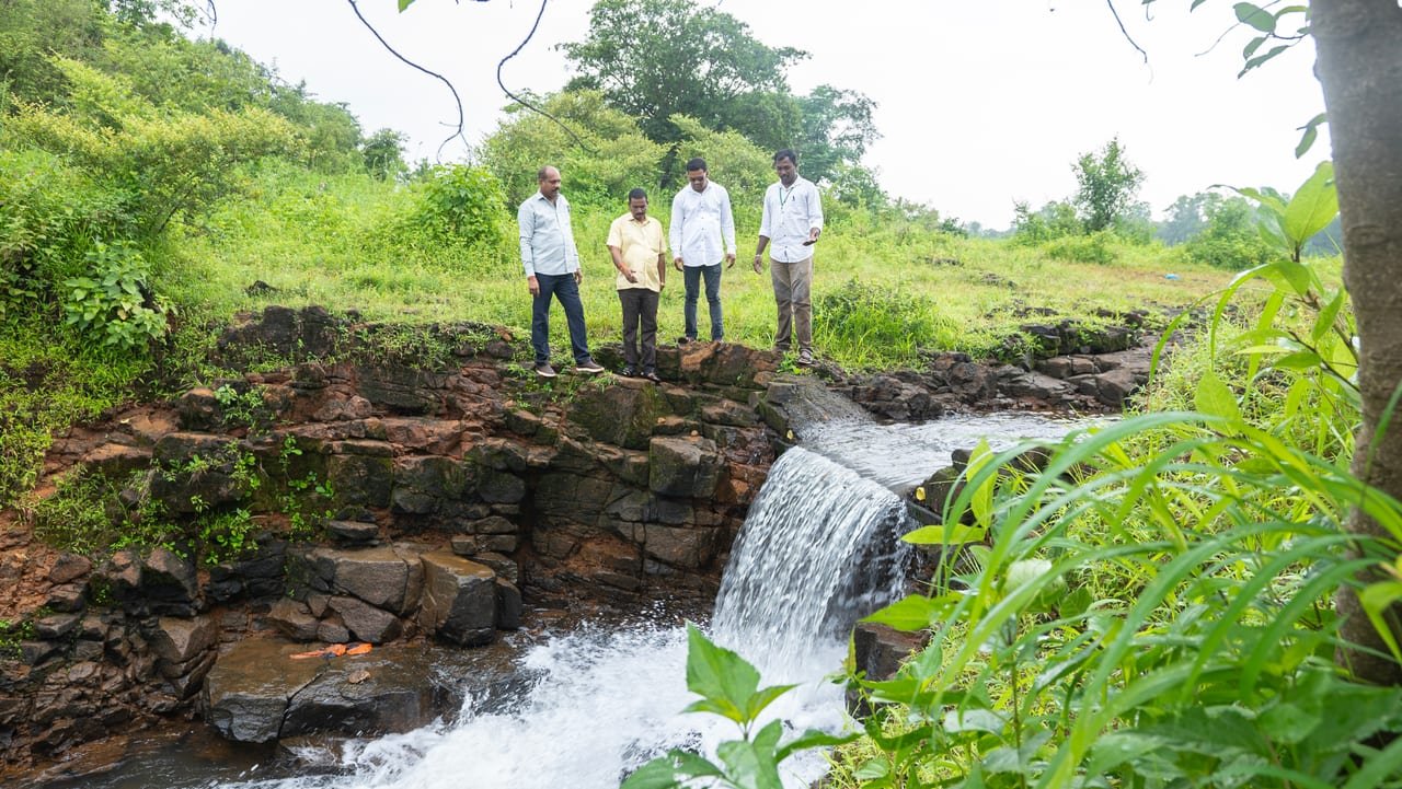 Three men on the rocks above a small waterfall on a stream