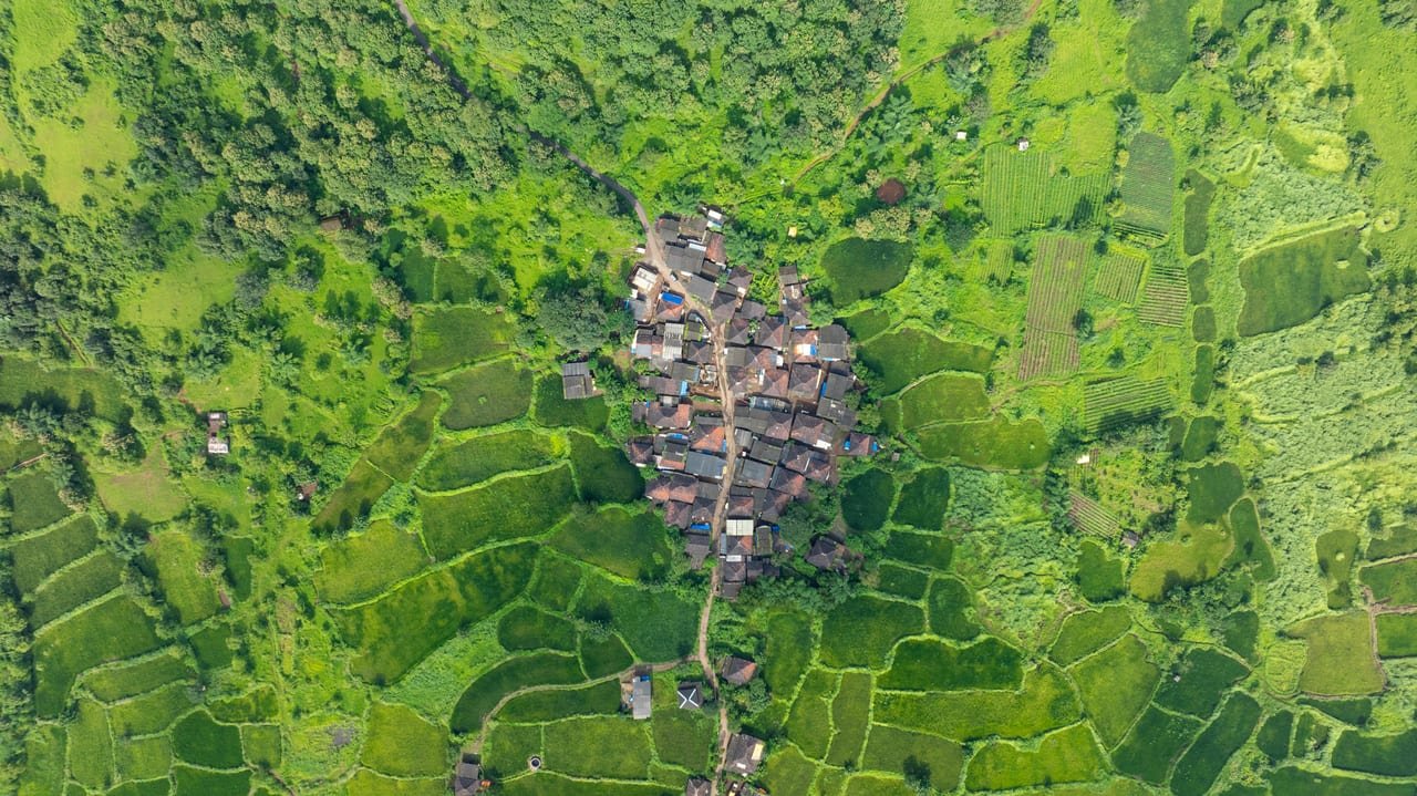 Aerial view of a village cluster ringed by green paddy terraces