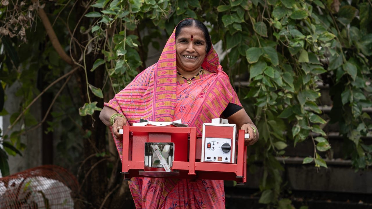 A smiling woman holding a red battery-operated machine