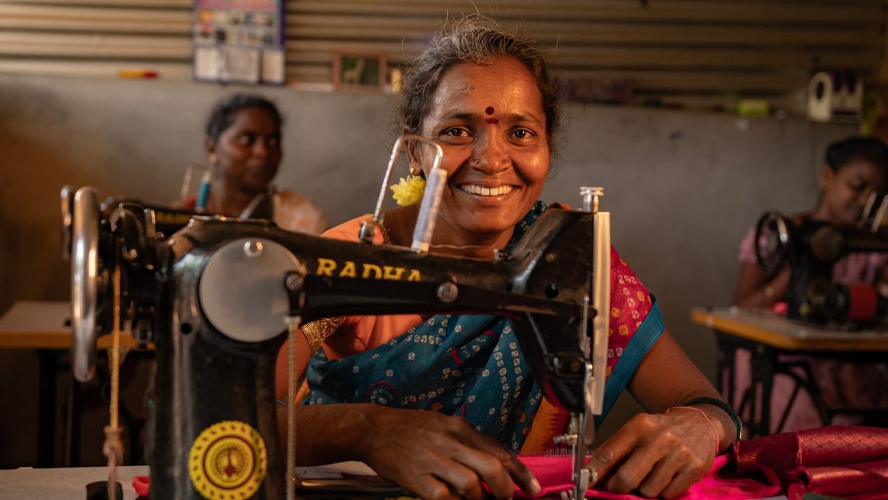 A smiling woman at her sewing machine in a tailoring unit