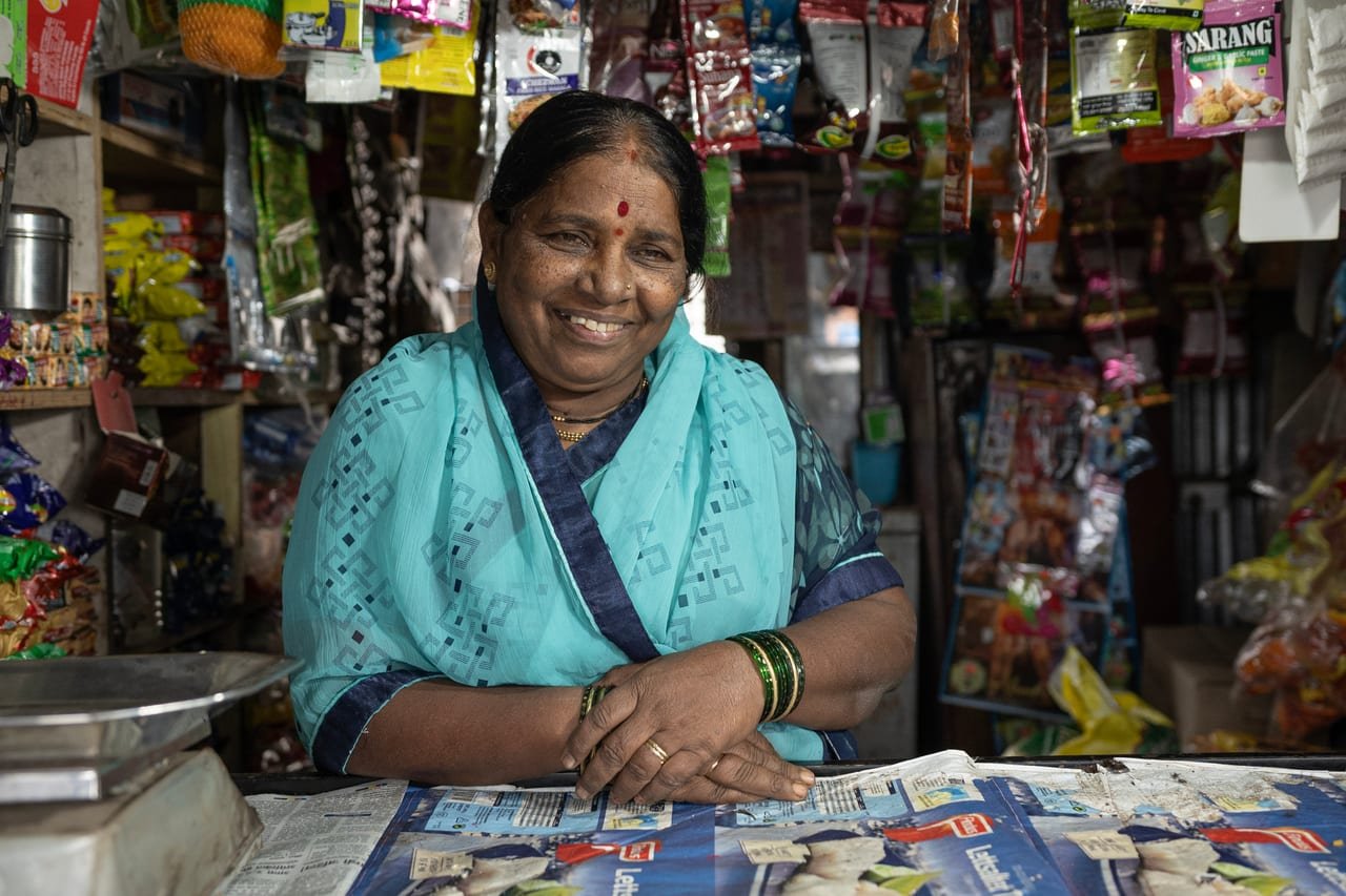 A smiling woman behind the counter of her village grocery shop