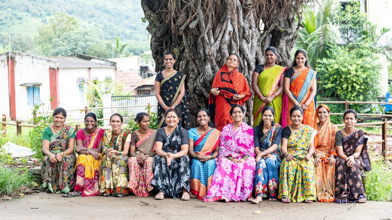 Women from a village group gathered under a large banyan tree