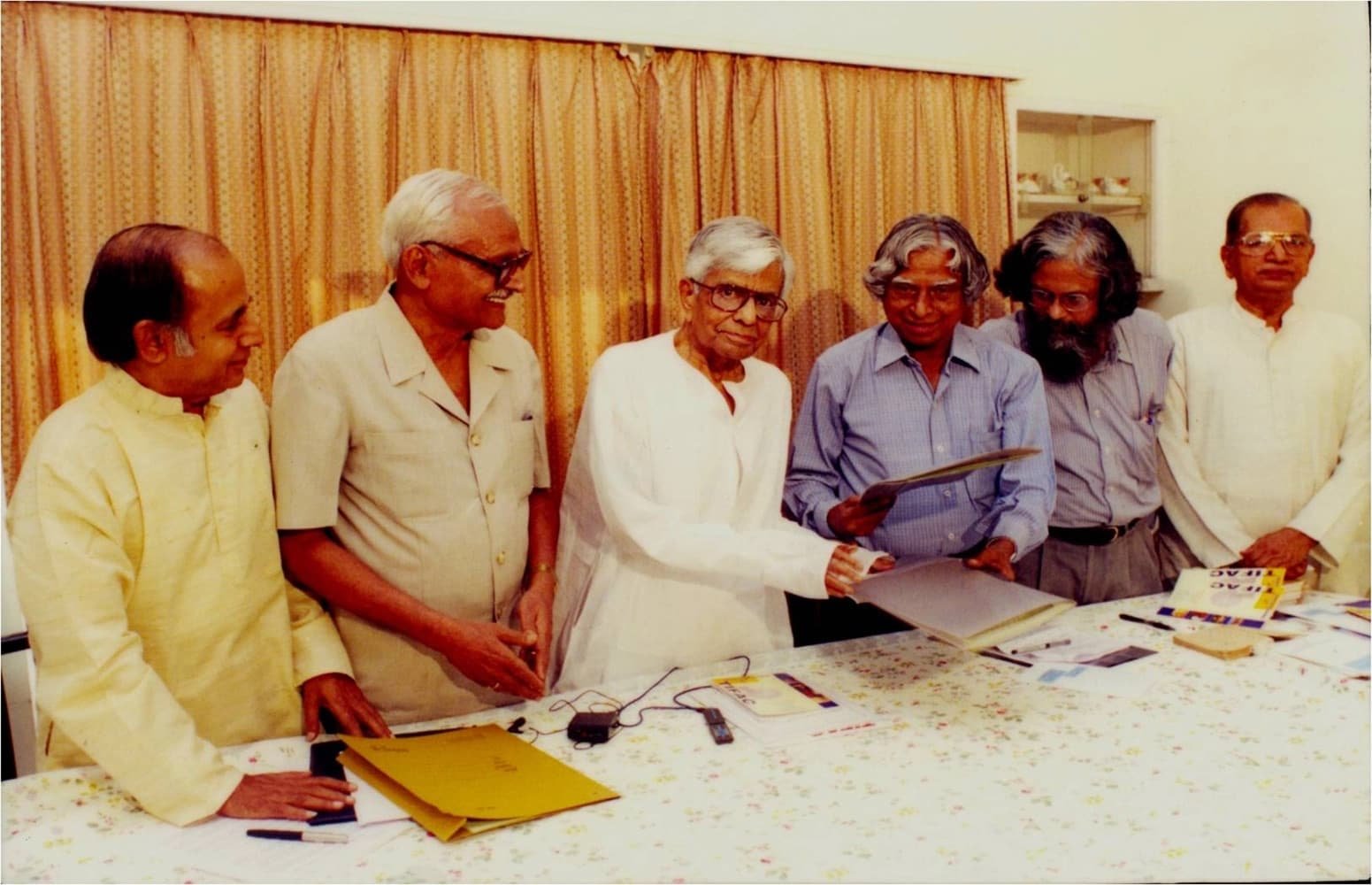 A group of dignitaries gathered around a table, reviewing a document